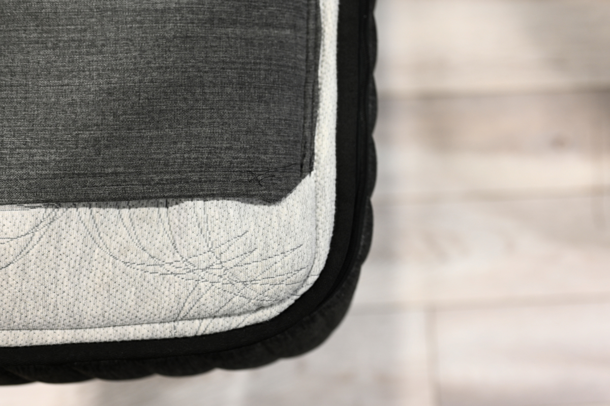 Top-down close-up of an Ausbeds mattress edge, highlighting the durable stitching where the patterned cover meets the black side panel.