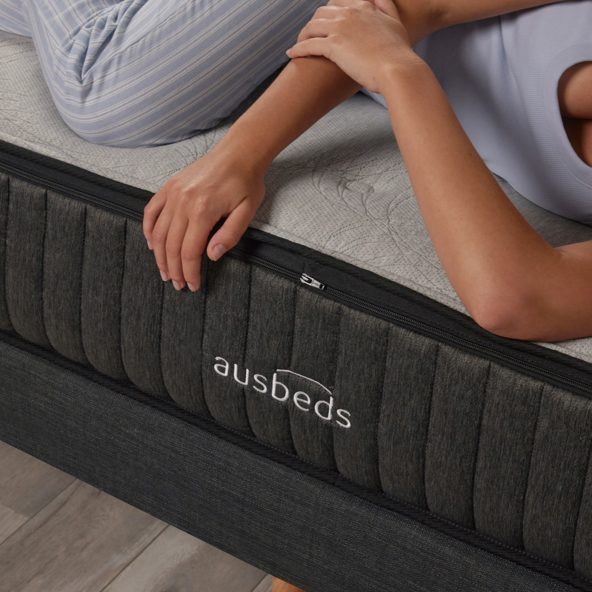 Model lying on side, closeup of logo on mattress