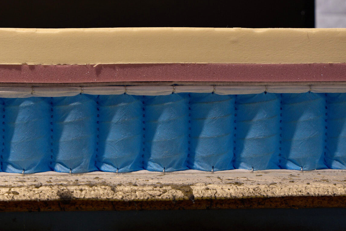 Inside view of the Ausbeds Cooper mattress - showing natural latex comfort layer, purple foam, and honeycomb pocket spring unit.